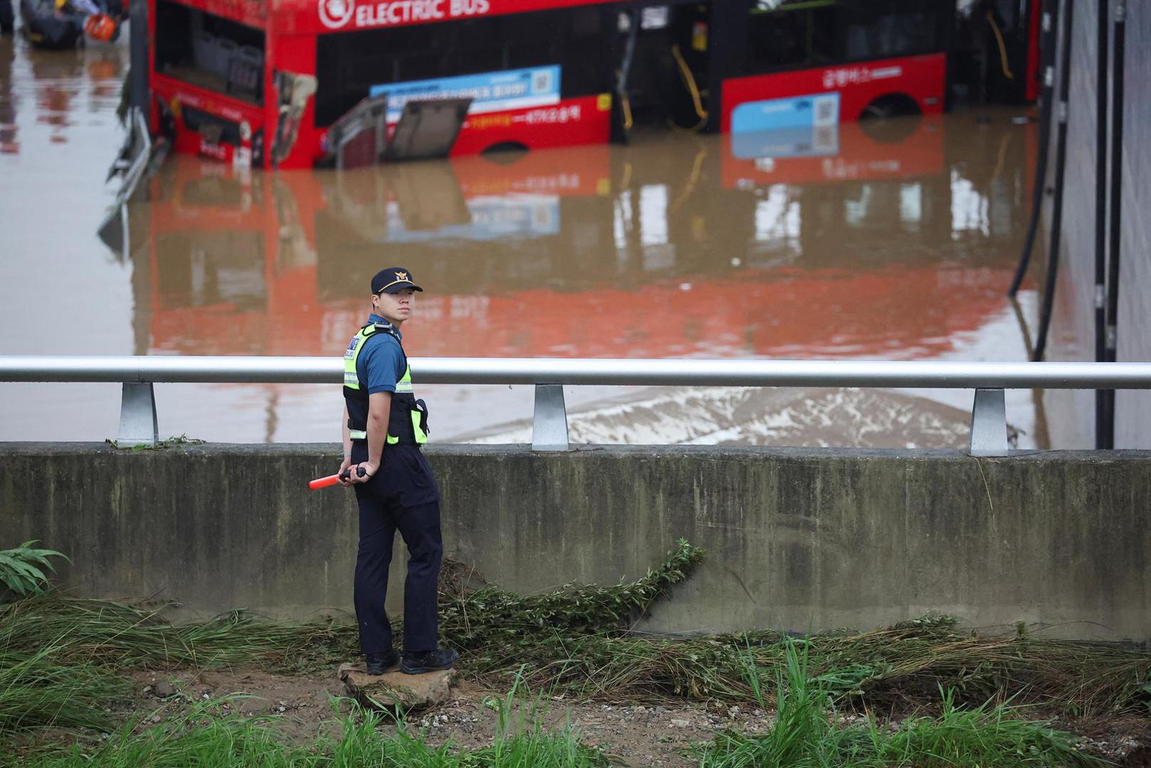 A police officer looks on near a recovered electric bus during a search and rescue operation near an underpass that has been submerged by a flooded river caused by torrential rain in Cheongju, South Korea, July 16, 2023.   REUTERS/Kim Hong-ji Photo: KIM HONG-JI/REUTERS