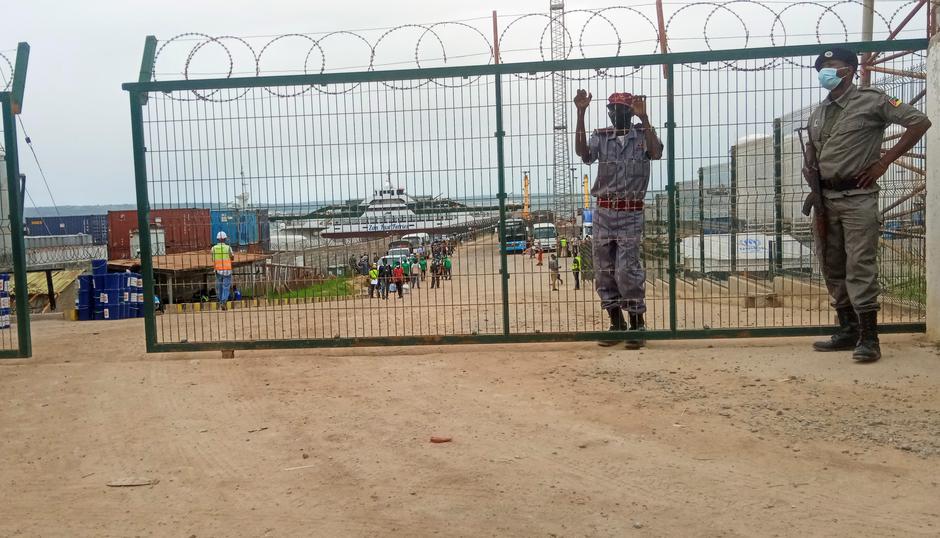 Officials stand guard as a ship carrying more than 1,000 people fleeing an attack on the town of Palma, docks in Pemba