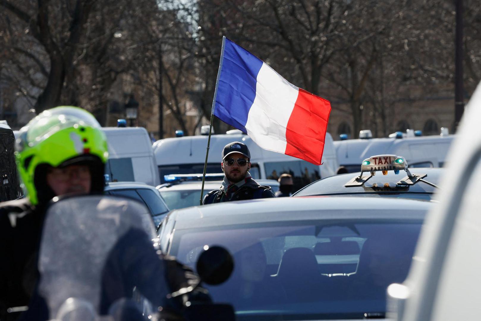 A protester waves a French flag on the Champs-Elysees avenue as cars parade during their "Convoi de la liberte" (The Freedom Convoy), a vehicular convoy to protest coronavirus disease (COVID-19) vaccine and restrictions in Paris, France, February 12, 2022. REUTERS/Benoit Tessier Photo: BENOIT TESSIER/REUTERS