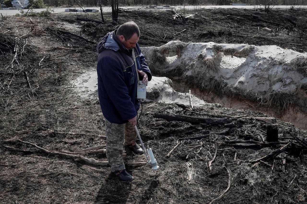 A dosimetrist measures the level of radiation around trenches dug by the Russian military in an area with high levels of radiation called the Red Forest near the Chernobyl Nuclear Power Plant, in Chernobyl