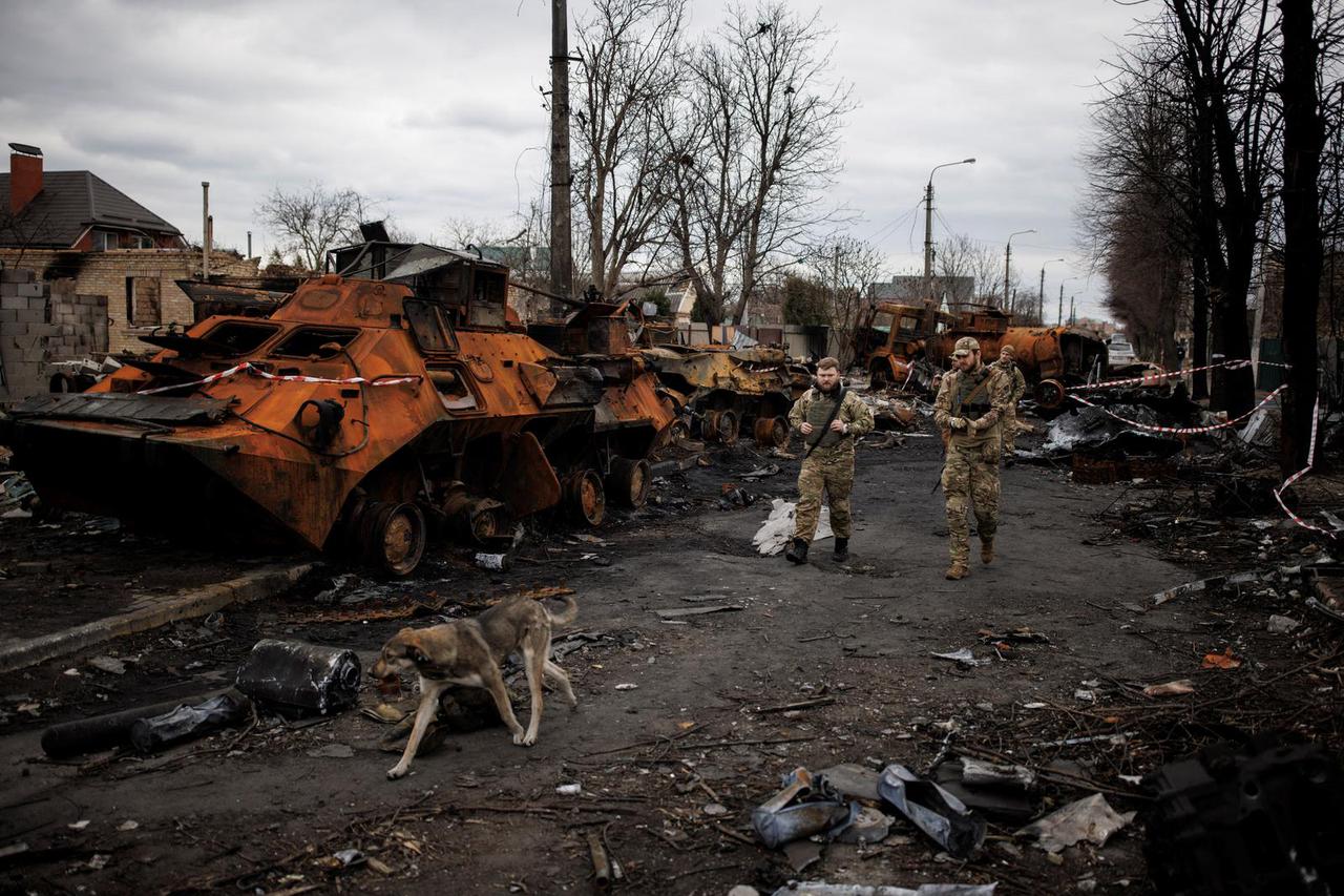 Ukrainian soldiers walk next to destroyed Russian tanks and armoured vehicles in Bucha