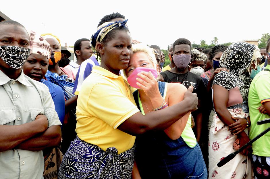 A woman is comforted by friends after a ship carrying more than 1,000 people fleeing an attack claimed by Islamic State-linked insurgents on the town of Palma, docks in Pemba