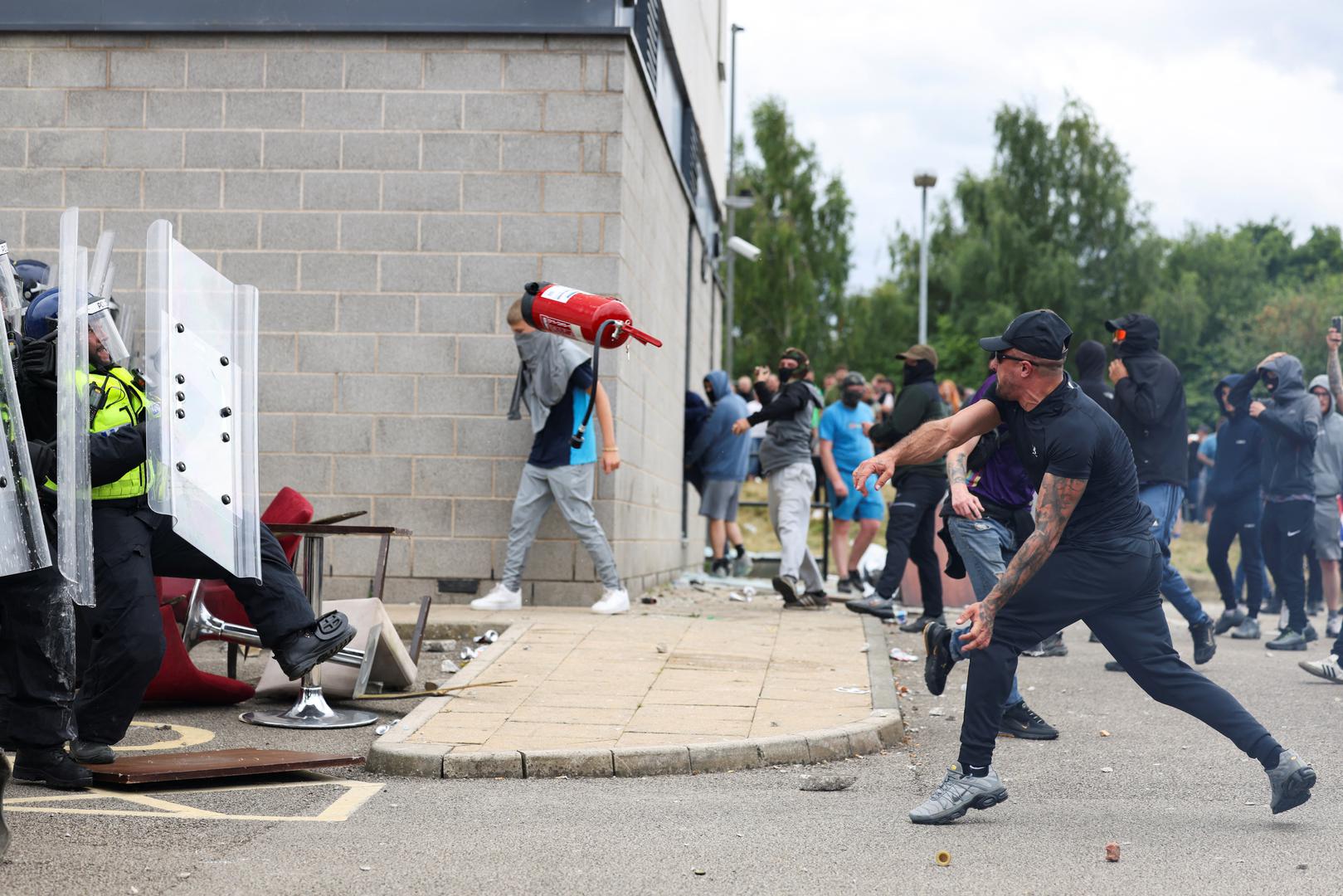 A protester throws a fire extinguisher at the police outside a hotel in Rotherham, Britain, August 4, 2024. REUTERS/Stringer Photo: STRINGER/REUTERS