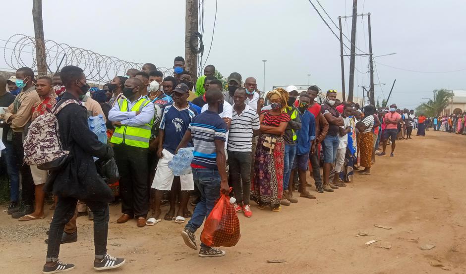 People wait as a ship carrying more than 1,000 people fleeing an attack on the town of Palma, docks in Pemba