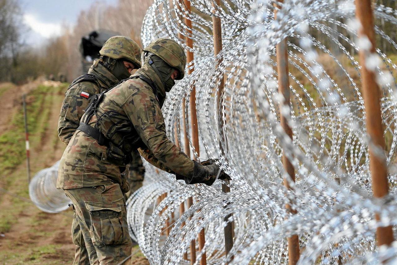 FILE PHOTO: Soldiers build razor wire fence on Poland's border with Russia's exclave of Kaliningrad near Bolcie