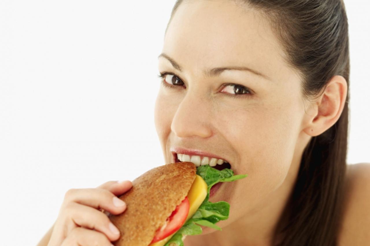 'Portrait of a young woman biting a sandwich'