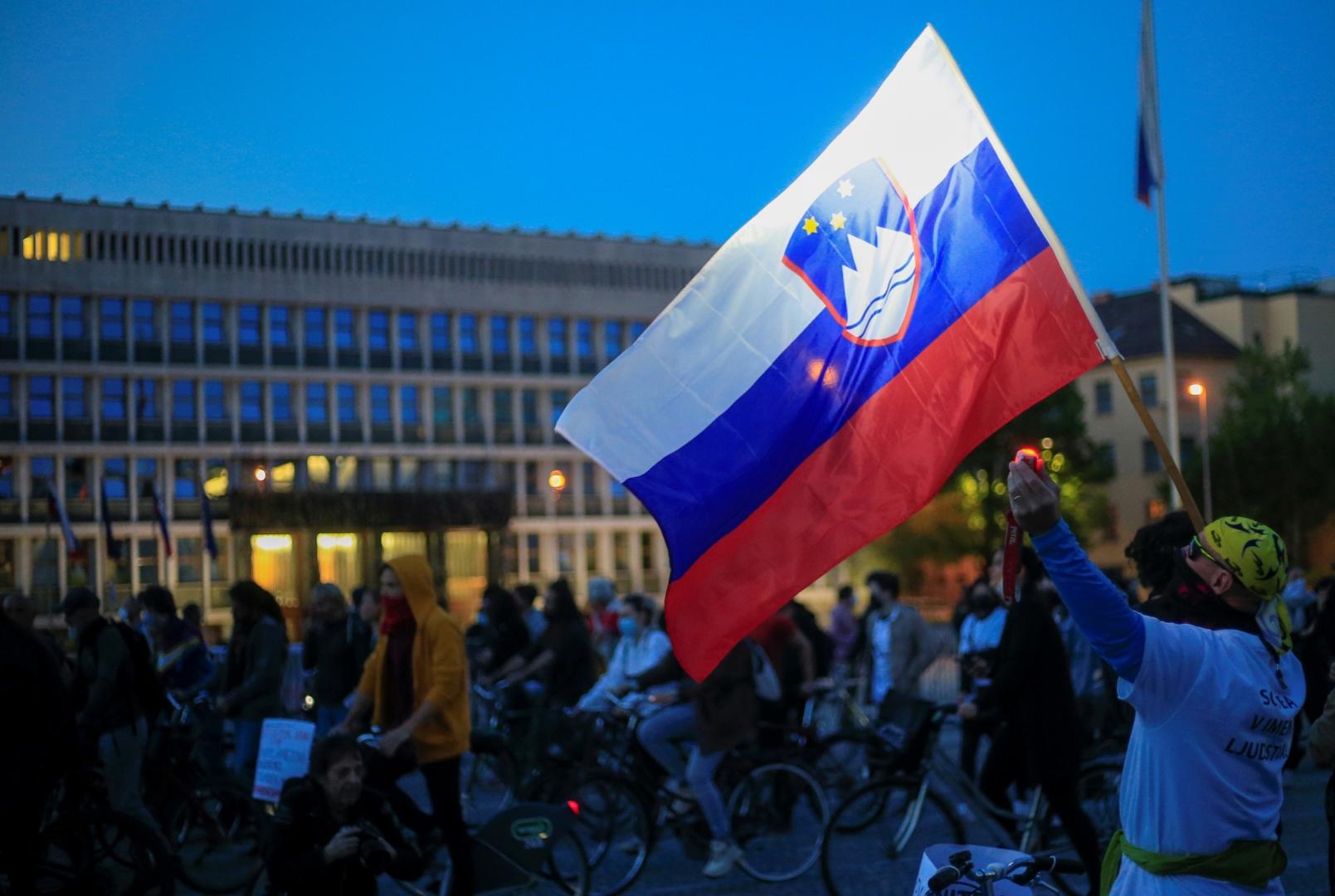 Protesters ride bicycles during an anti-government protest in Ljubljana A protester covering his mouth with a scarf holds a Slovenian flag during an anti-government demonstration, as the spread of the coronavirus disease (COVID-19) continues, in Ljubljana, Slovenia May 8, 2020. REUTERS/Borut Zivulovic BORUT ZIVULOVIC