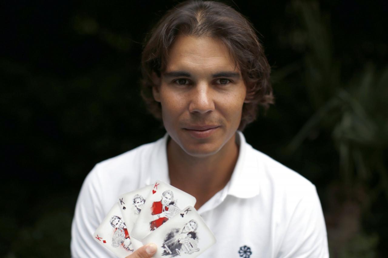 'Spanish tennis player Rafa Nadal poses with playing cards depicting some of his 11 Grand Slam victories after an interview with Reuters in Madrid, September 18, 2012. Rafa Nadal\'s steady recuperatio