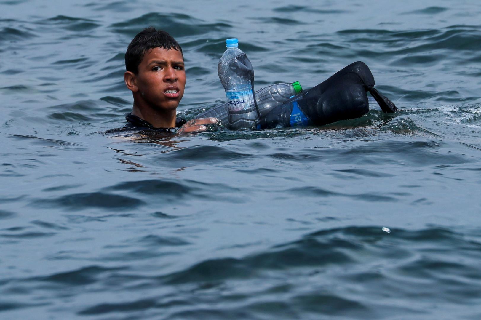 Thousands of migrants cross the Spanish-Moroccan border A Moroccan boy swims using bottles as a float, near the fence between the Spanish-Moroccan border, after thousands of migrants swam across the border, in Ceuta, Spain, May 19, 2021. Picture taken May 19, 2021. REUTERS/Jon Nazca JON NAZCA