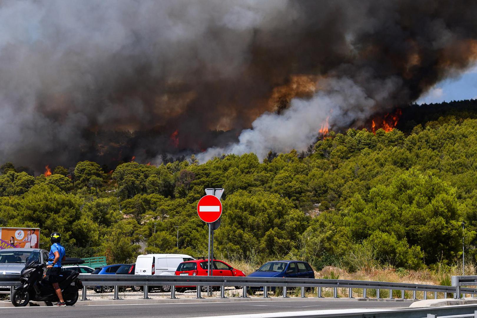 06.08.2024., Sibenik - Nesto prije 13 sati izbio je pozar u borovoj sumi u sibenskom naselju Rokici, odmah pokraj bolnice i stambenih kuca. Na terenu su vatrogasci i policija, a pozvana je i pomoc iz zraka. Suma se nalazi iznad Jadranske magistrale koja je zbog pozara zatvorena za sav promet. Photo: Hrvoje Jelavic/PIXSELL