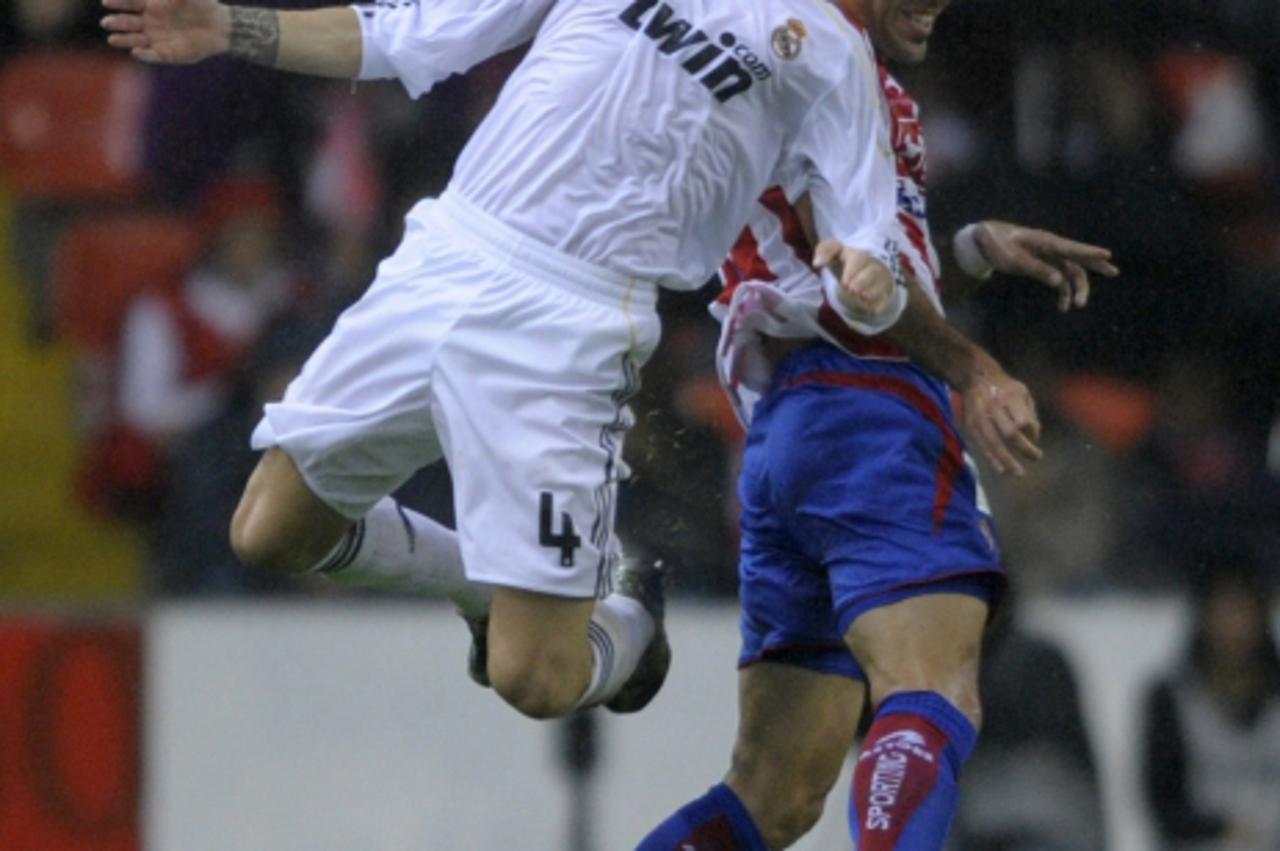 'Real Madrid\'s defender Sergio Ramos (L) jumps for the ball with Sporting Gijon\'s Croatian forward Mate Bilic (R) during their Spanish first league football match at the Molinon Stadium in Gijon, on