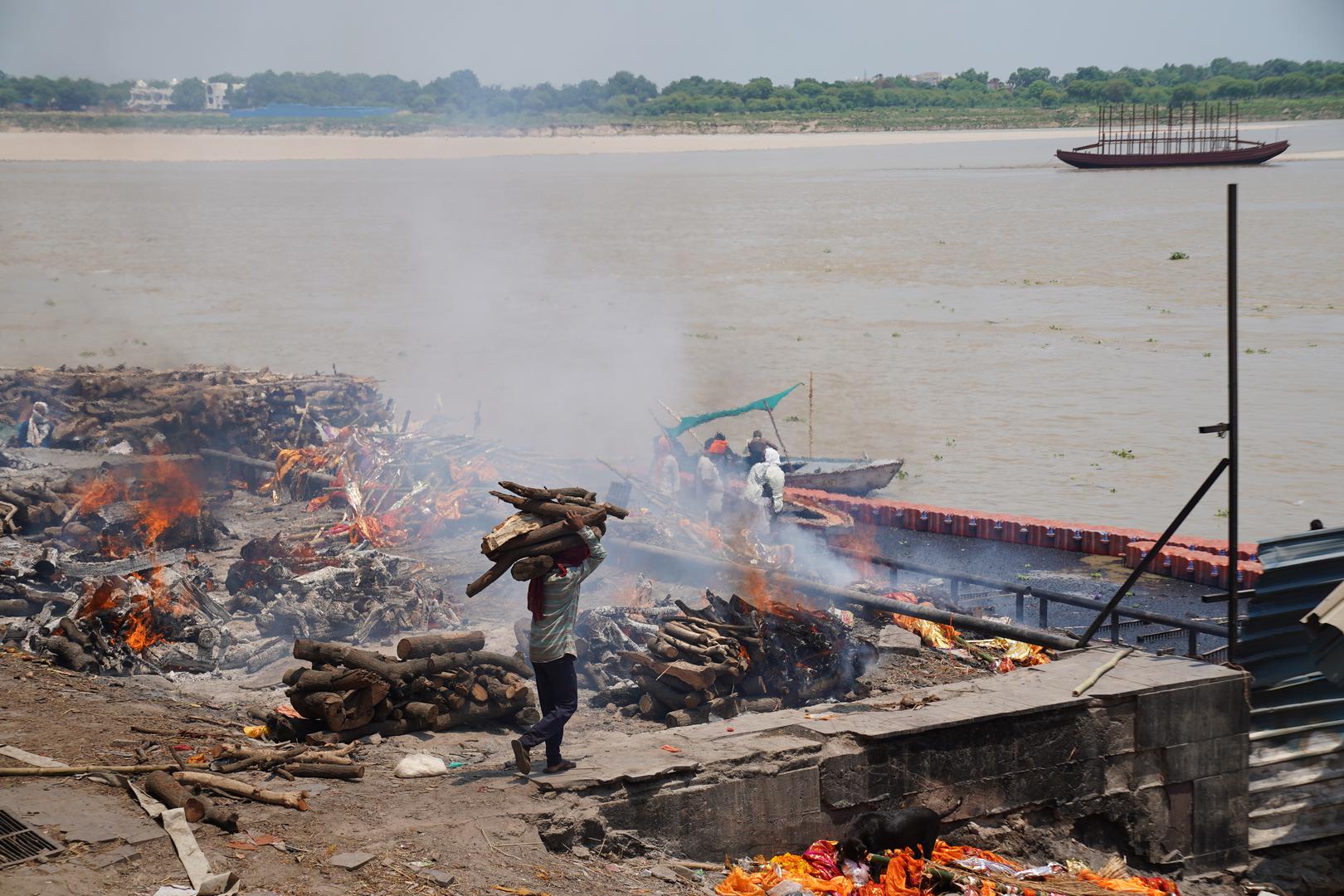 19 July 2024, India, Varanasi: A man brings more wood to pyres where corpses are burned by the Ganges. Photo: Anne-Sophie Galli/dpa Photo: Anne-Sophie Galli/DPA