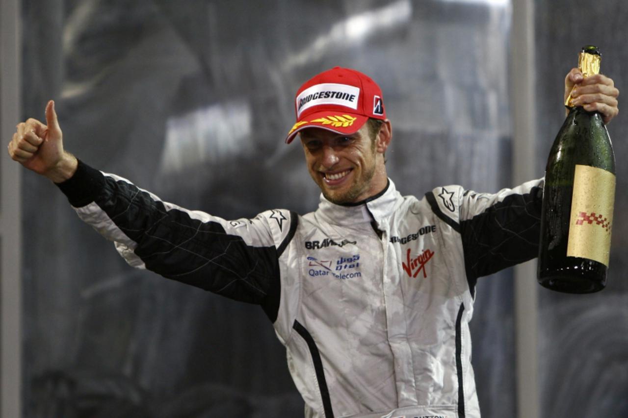 'Brawn GP Formula One driver Jenson Button of Britain  celebrates his third place at the Abu Dhabi F1 Grand Prix at the Yas Marina circuit November 1, 2009.  REUTERS/Steve Crisp (UNITED ARAB EMIRATES 