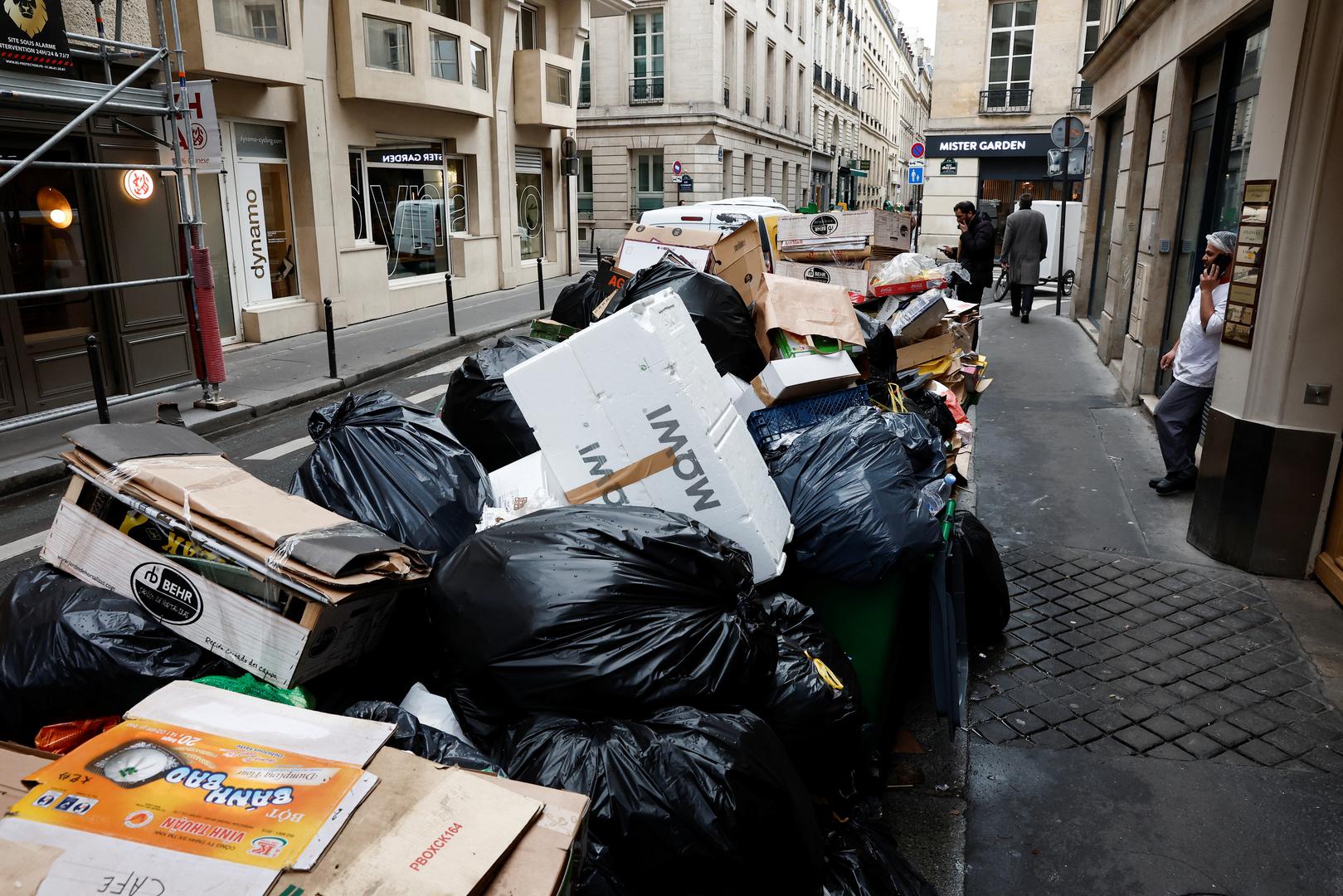 People walk in a street where garbage cans are overflowing, as garbage has not been collected, in Paris, France March 13, 2023. REUTERS/Benoit Tessier Photo: BENOIT TESSIER/REUTERS