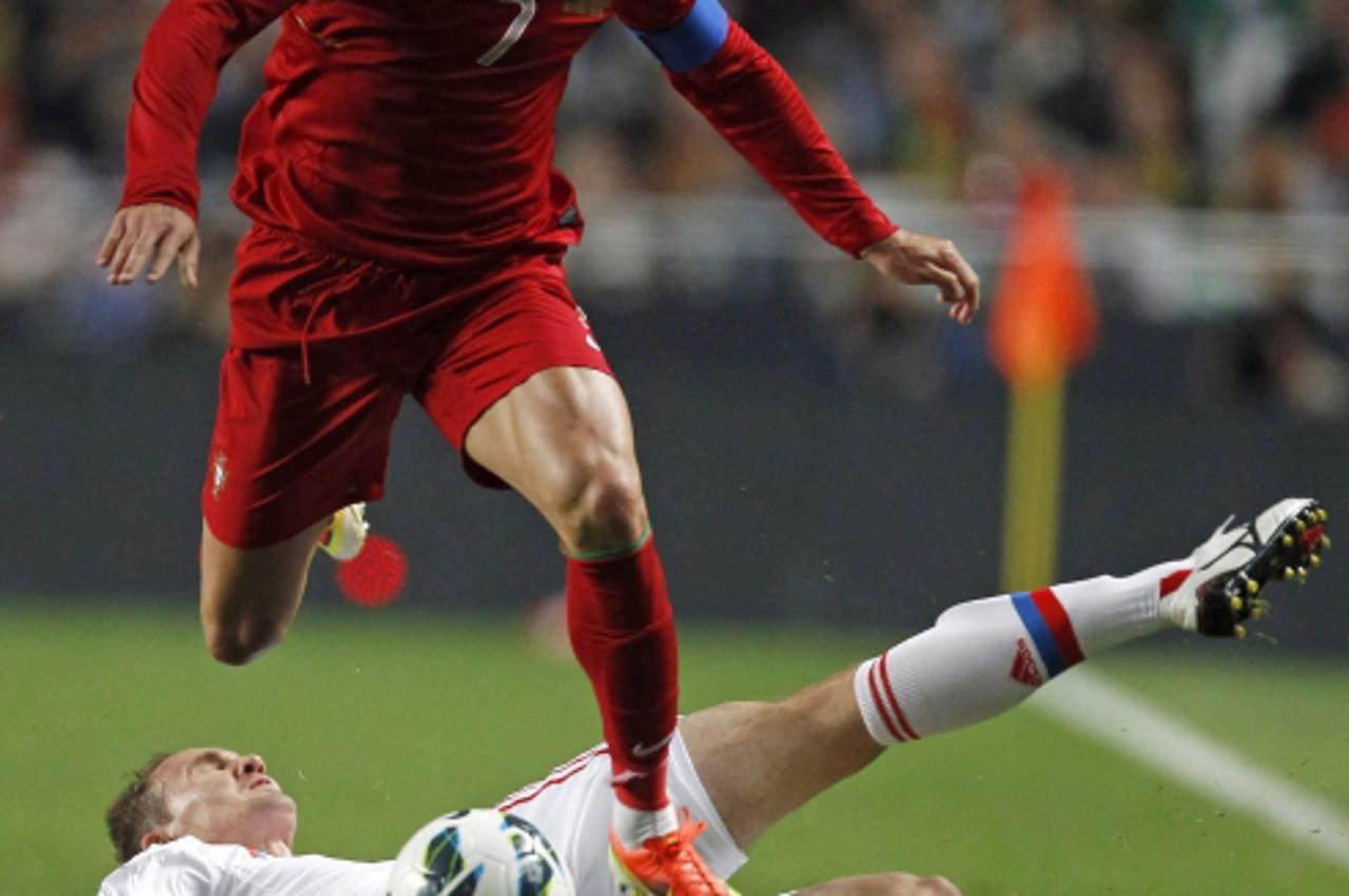 'Portugal\'s Cristiano Ronaldo controls the ball as he passes over Russia\'s Alexey Kozlov at Luz stadium during their 2014 World Cup qualifying soccer match in Lisbon June 7, 2013. REUTERS/Jose Manue