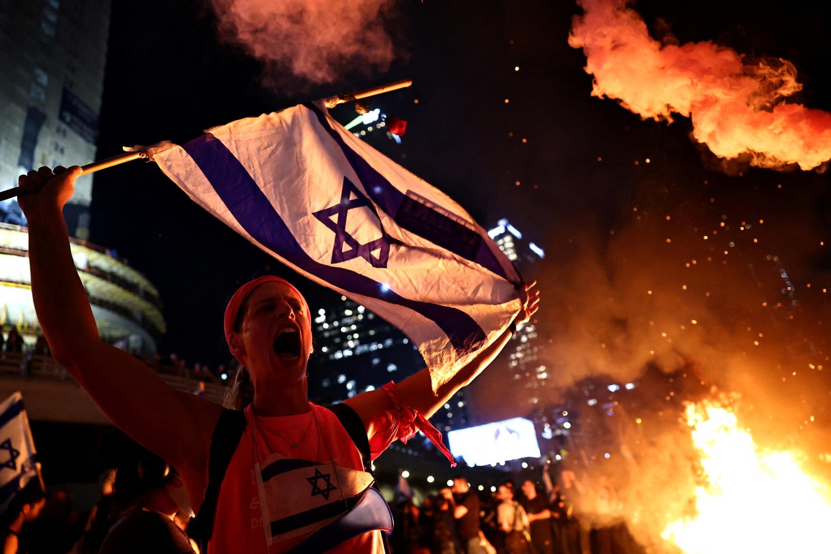 A person holds an Israeli flag as people demonstrate after Israeli Prime Minister Benjamin Netanyahu sacked his defense minister, Yoav Gallant, citing lack of trust, in Tel Aviv, Israel November 5, 2024. REUTERS/Thomas Peter Photo: Thomas Peter/REUTERS