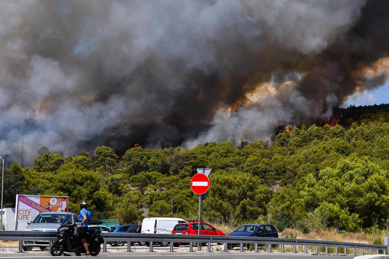 06.08.2024., Sibenik - Nesto prije 13 sati izbio je pozar u borovoj sumi u sibenskom naselju Rokici, odmah pokraj bolnice i stambenih kuca. Na terenu su vatrogasci i policija, a pozvana je i pomoc iz zraka. Suma se nalazi iznad Jadranske magistrale koja je zbog pozara zatvorena za sav promet. Photo: Hrvoje Jelavic/PIXSELL