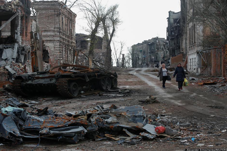 People walk near damaged buildings in Mariupol