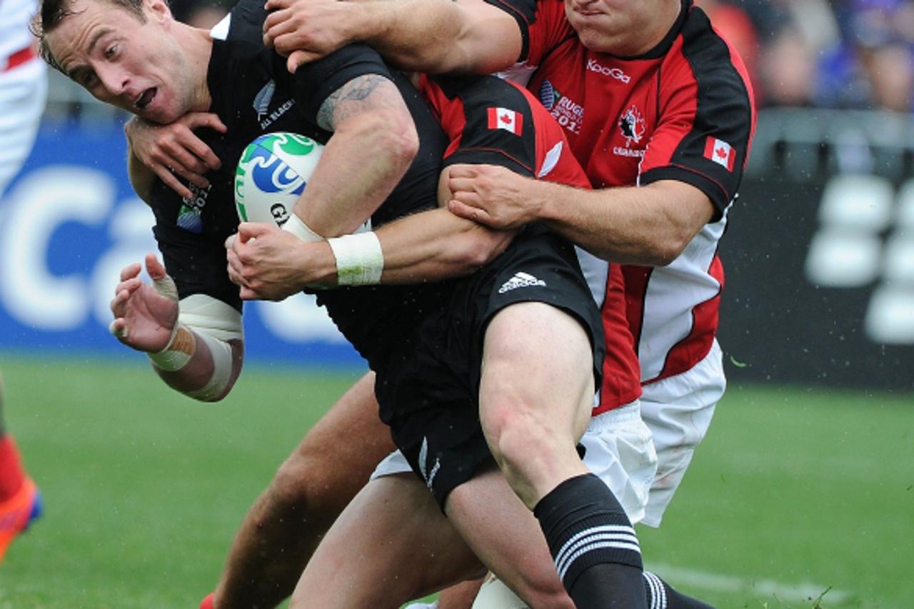 'New Zealand All Black scrum-half Jimmy Cowan is tackled by Canada\'s prop Jason Marshall (R) during the 2011 Rugby World Cup pool A match New Zealand vs Canada at the Wellington Regional Stadium in W