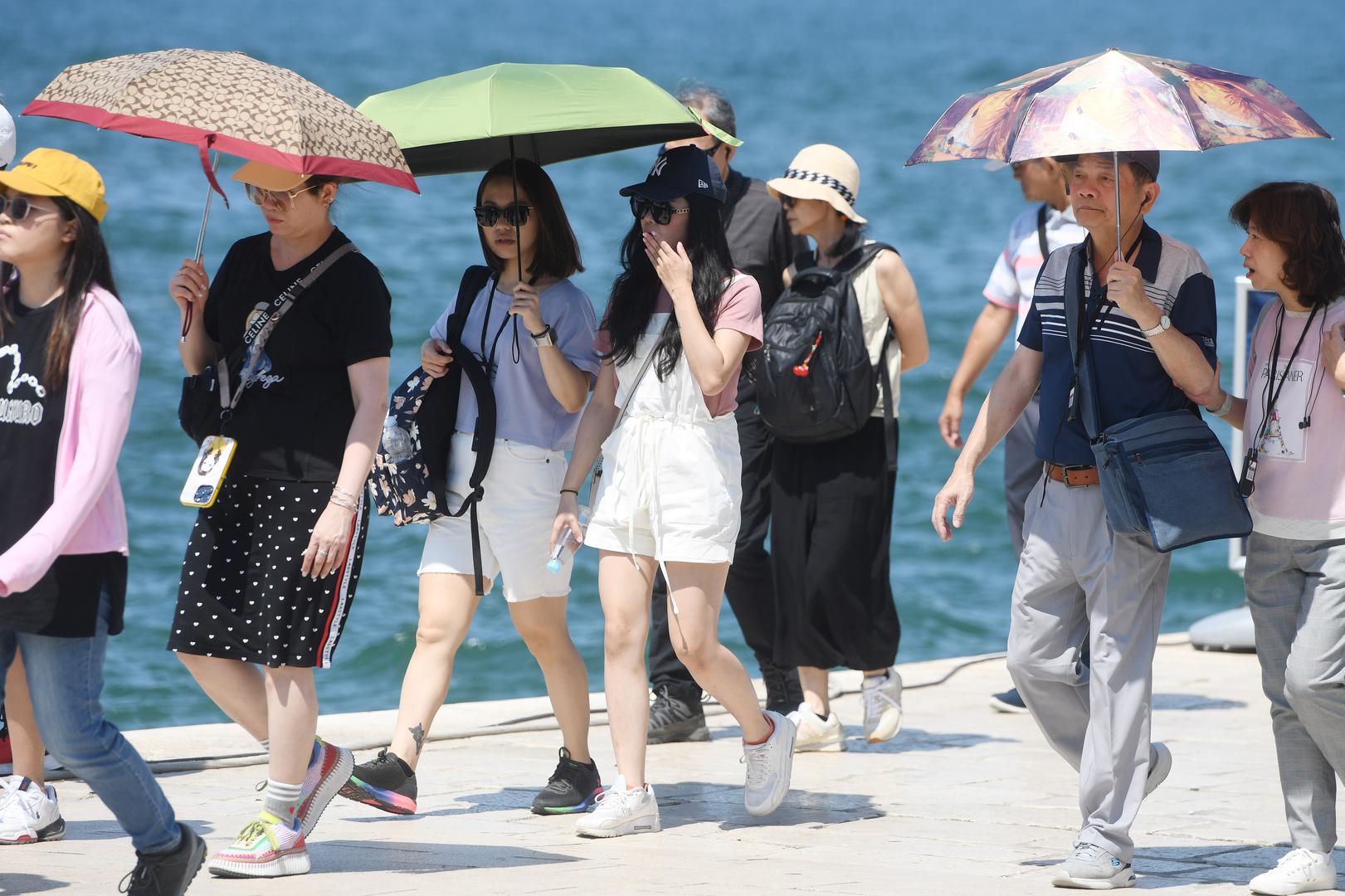 27.06.2023., Sibenik - Spas od vrucina turisti potrazili ispod kisobrana. Photo: Hrvoje Jelavic/PIXSELL