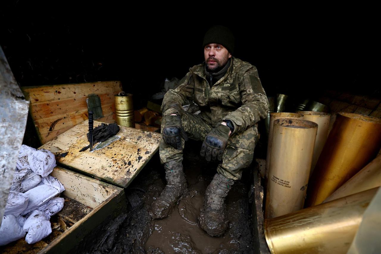 A Ukrainian serviceman of a fire platoon sits inside a hiding of a trench near the frontline