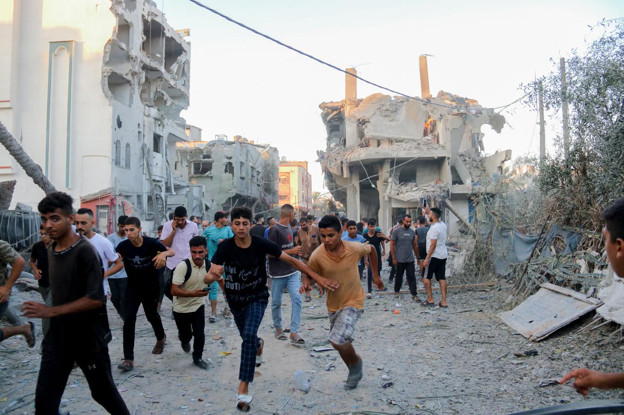 Palestinian people run away during an Israeli bombardment in Deir al Balah, Gaza