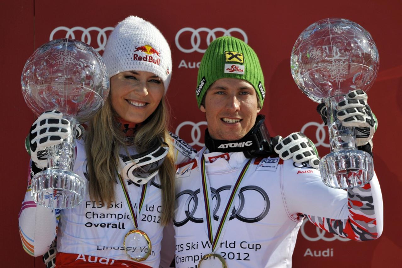 'Overall World Cup winners US Lindsey Vonn (L) and Austria\'s Marcel Hirscher pose with their World Cup trophies in the finish area after the Alpine skiing World Cup finals in Schladming on March 18, 