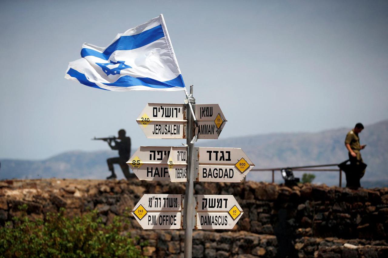 FILE PHOTO: An Israeli soldier stands next to signs pointing out distances to different cities, on Mount Bental, an observation point in the Israeli-occupied Golan Heights that overlooks the Syrian side of the Quneitra crossing