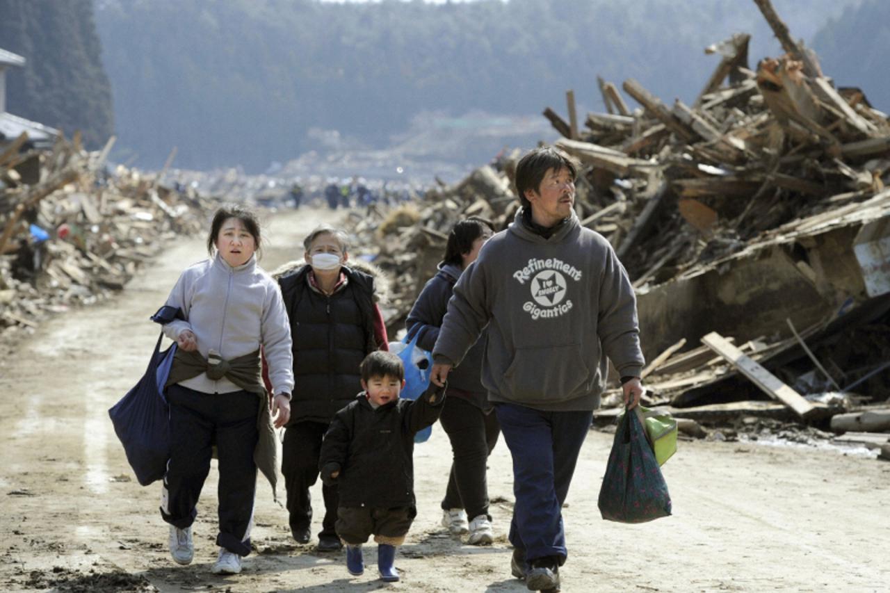 \'A family walks past buildings destroyed by a tsunami in Minamisanriku, Miyagi Prefecture, in northern Japan after the magnitude 8.9 earthquake struck the area, March 13, 2011.   REUTERS/Kyodo (JAPAN