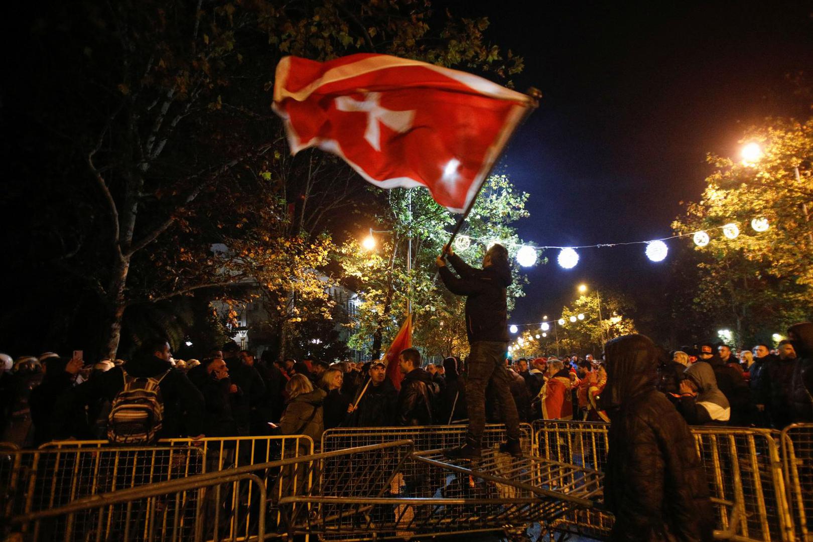 A protestor waves a flag on top of the breached barrier during a protest against the adoption of a law to limit presidential powers in Podgorica, Montenegro, December 12, 2022. REUTERS/Stevo Vasiljevic Photo: STEVO VASILJEVIC/REUTERS