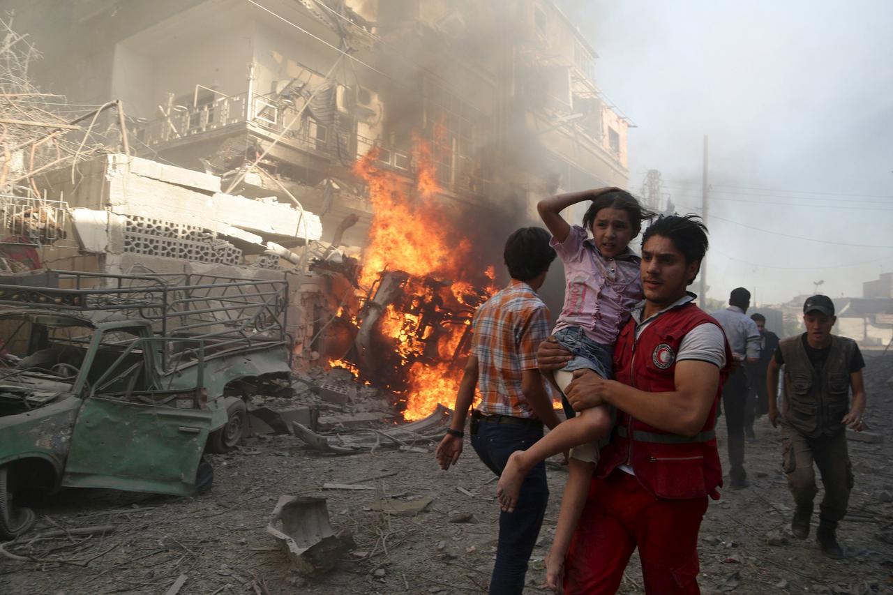 A member of the Syrian Arab Red Crescent carries a girl as they rush away from a site hit by what activists said were airstrikes by forces loyal to Syria's President Bashar al-Assad in the Douma neighborhood of Damascus, Syria August 24, 2015. REUTERS/Bas