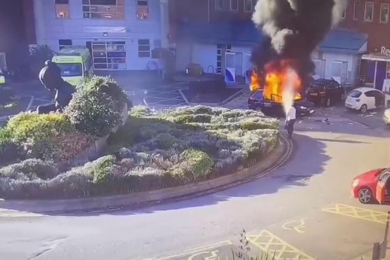 Surveillance camera footage shows a man extinguishing a burning taxi following an explosion, outside Liverpool Women's hospital