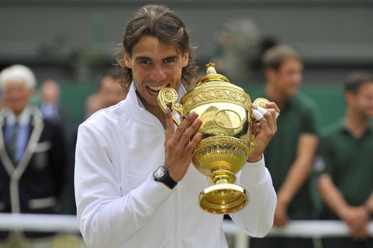 'Spain\'s Rafael Nadal bites the winners trophy as he poses for a photograph after defeating Tomas Berdych of the Czech Republic in the men\'s singles final at the 2010 Wimbledon tennis championships 