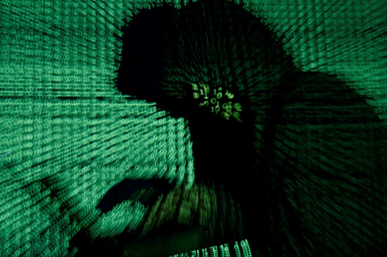 FILE PHOTO: Man holds laptop computer as cyber code is projected on him in this illustration picture