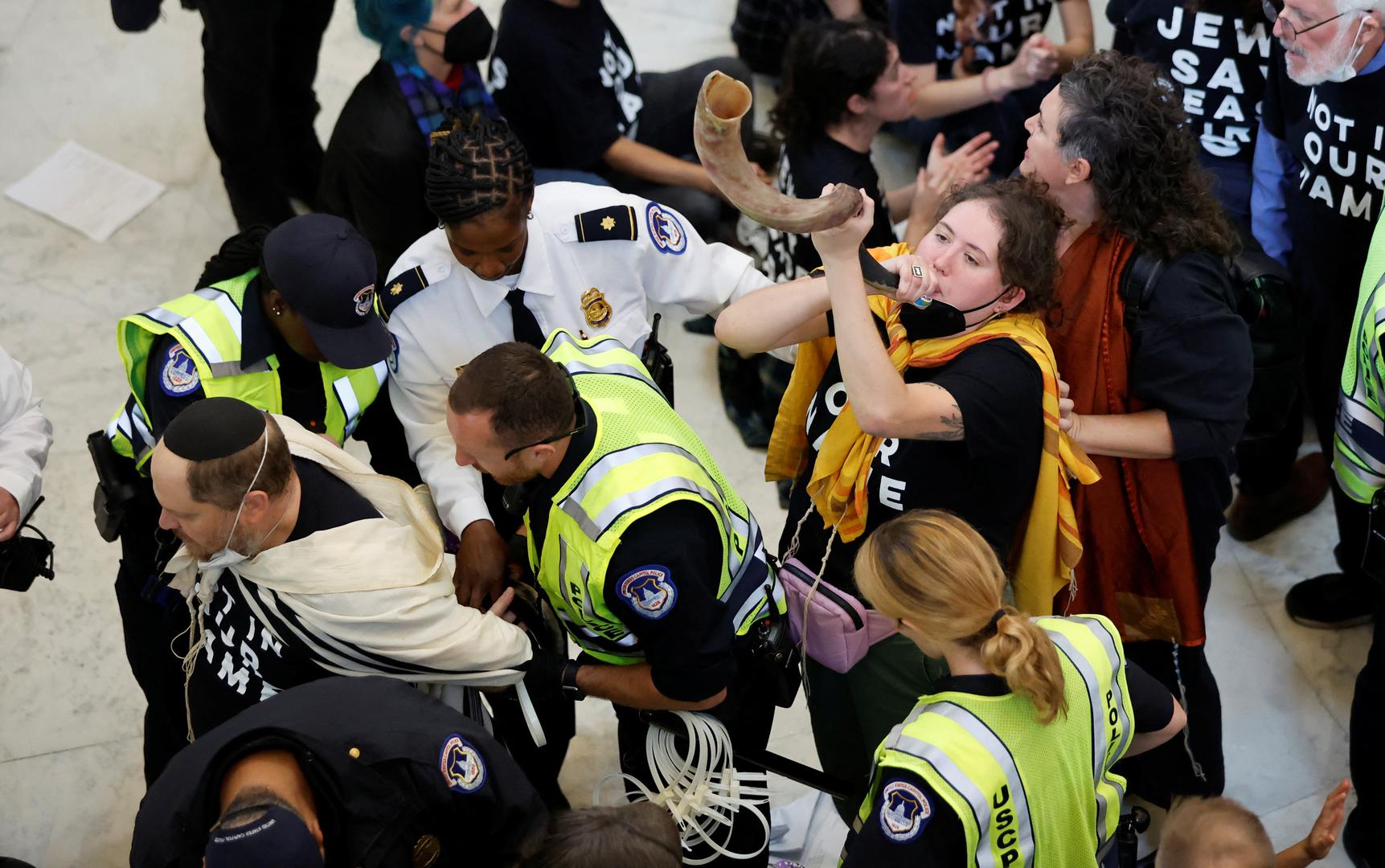 A protestor blows on a shofar horn demonstrators around her are detained by U.S. Capitol police officers during a civil disobedience action organized by a group called "Jewish Voice for Peace," calling for a cease fire in Gaza, while occupying the rotunda of the Cannon House office building on Capitol Hill in Washington, U.S., October 18, 2023. REUTERS/Jonathan Ernst Photo: JONATHAN ERNST/REUTERS