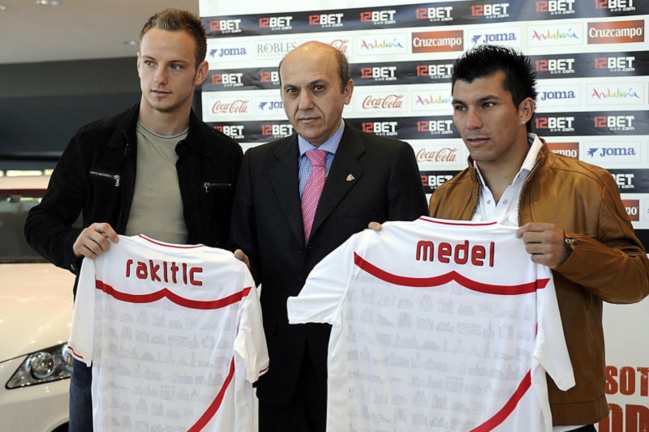 'Sevila FC\'s new signing football players, Chilean midfielder Gary Medel (R) and Croatian-Swiss midfielder Ivan Rakitic (L) gesture as they pose with Sevilla FC\'s president Jose Maria del Nido durin