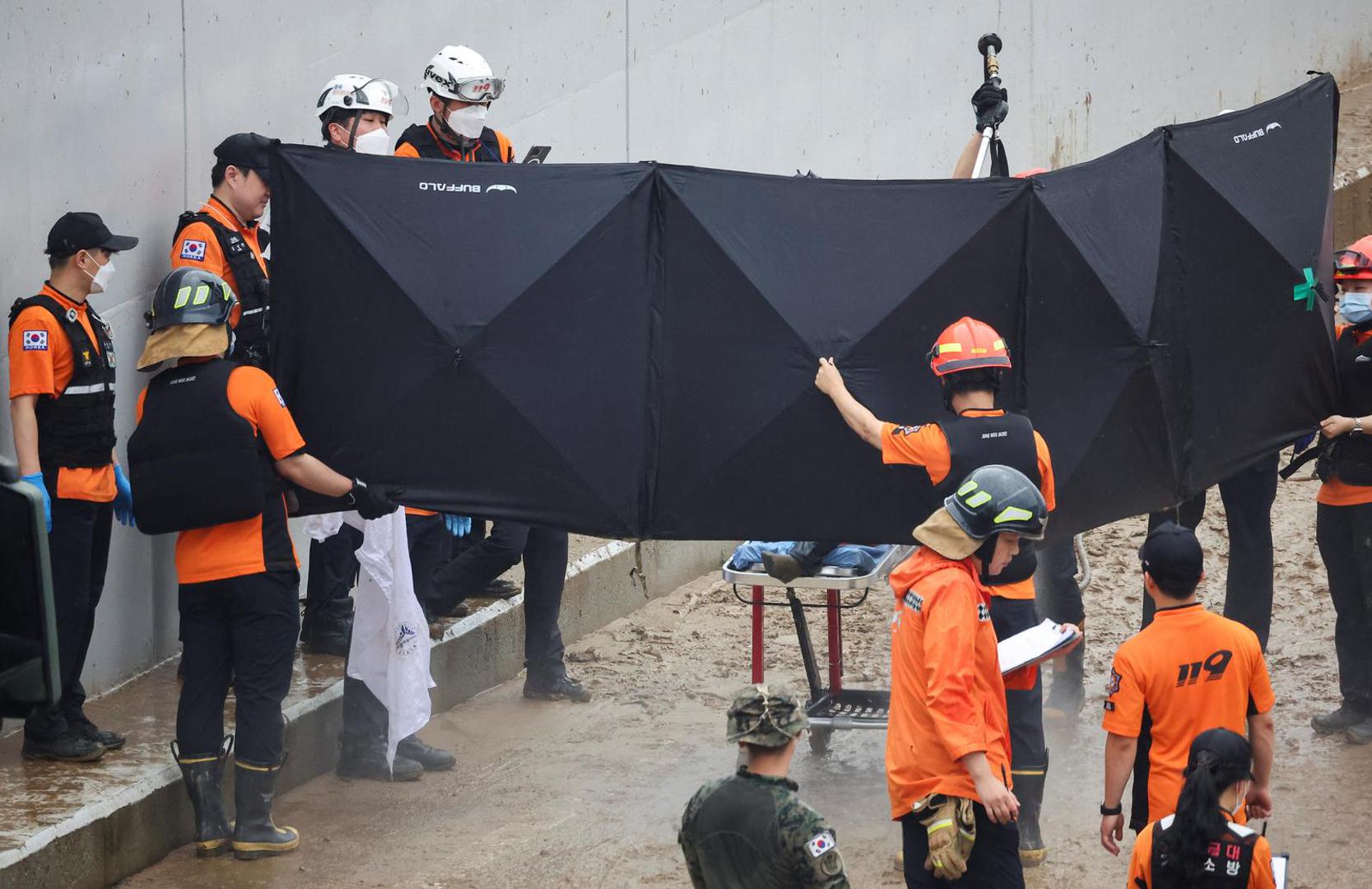 SENSITIVE MATERIAL. THIS IMAGE MAY OFFEND OR DISTURB Rescue workers remove mud from the body of a victim recovered during a search and rescue operation near an underpass that has been submerged by a flooded river caused by torrential rain in Cheongju, South Korea, July 16, 2023.   REUTERS/Kim Hong-ji Photo: KIM HONG-JI/REUTERS