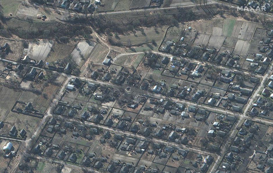 A satellite image shows a large crater in the middle of a residential area and destroyed homes, in Sukachi village, north of Kyiv