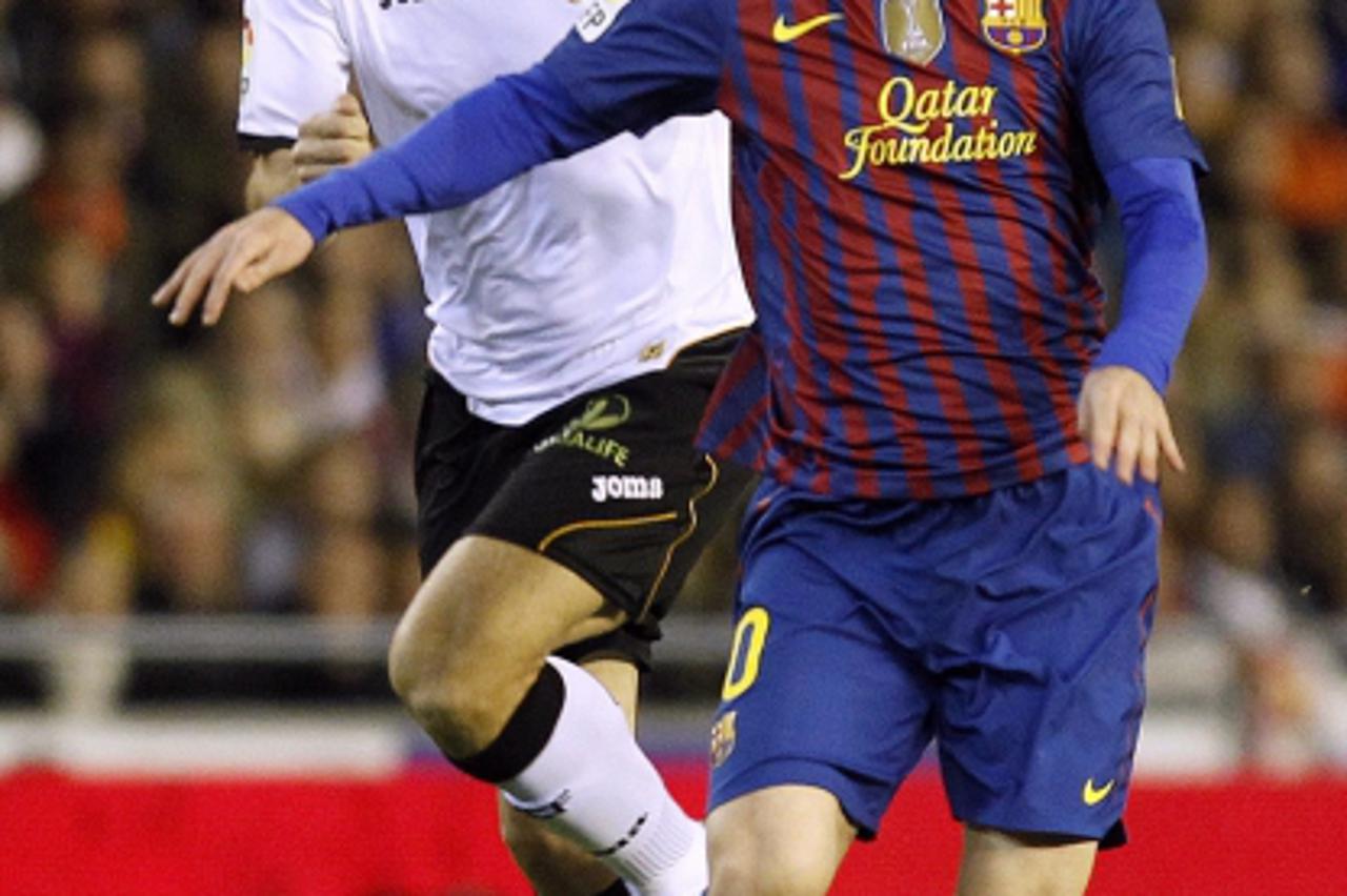 'Barcelona's Lionel Messi (R) is challenged by Valencia's David Albelda during their Spanish King's Cup semi-final first leg soccer match at Mestalla stadium in Valencia, February 1, 2012.    REUTE