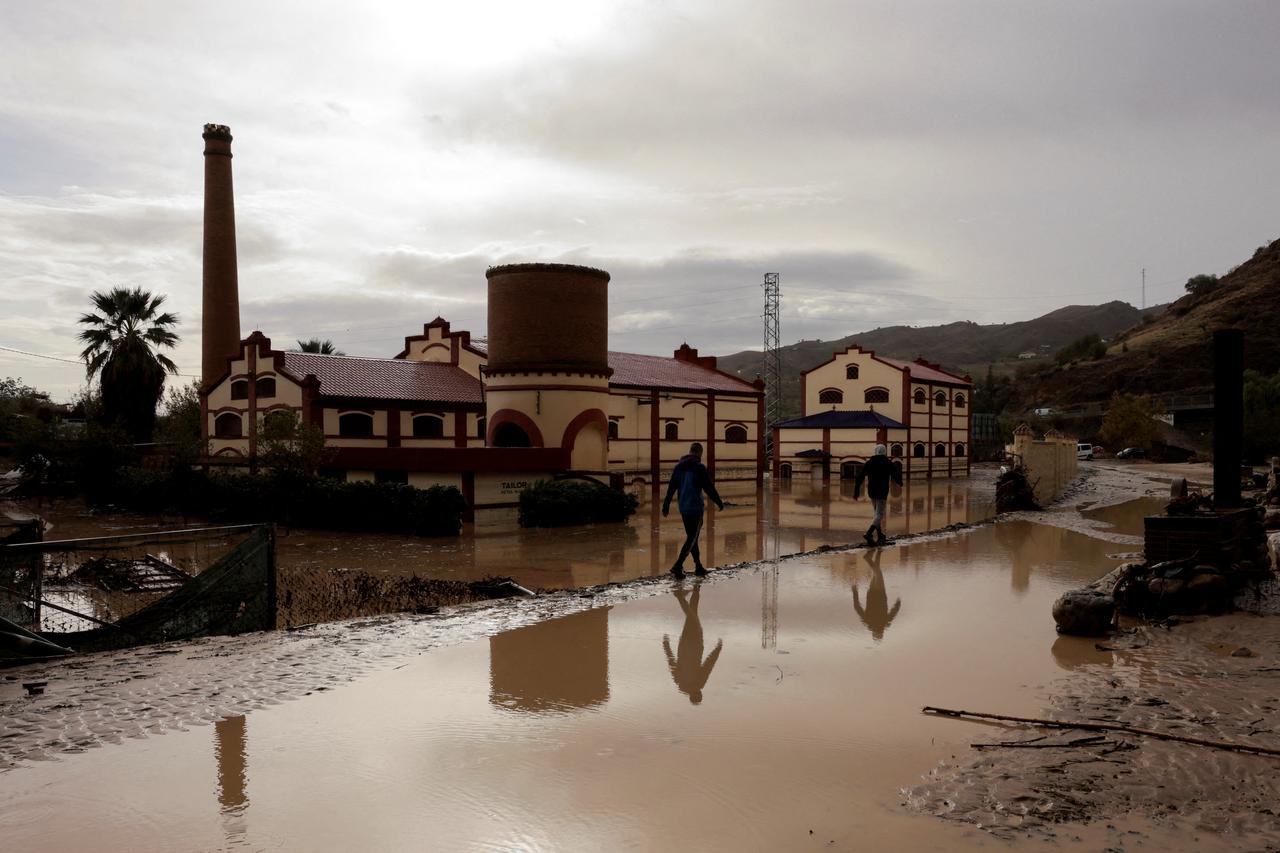 Men walk along a flooded area after heavy rains and floods in Alora