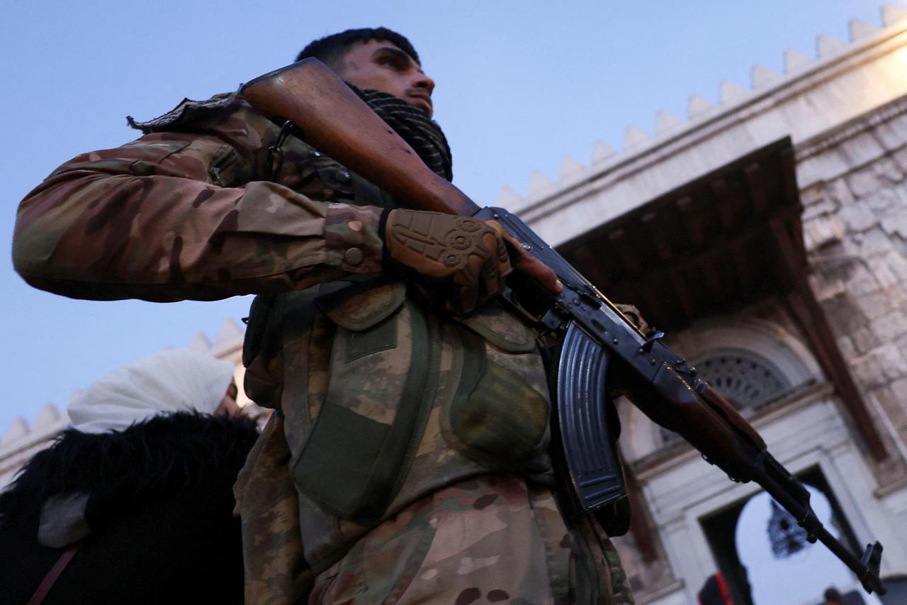 A rebel fighter holds his weapon in front off the Umayyad Mosque, in Damascus