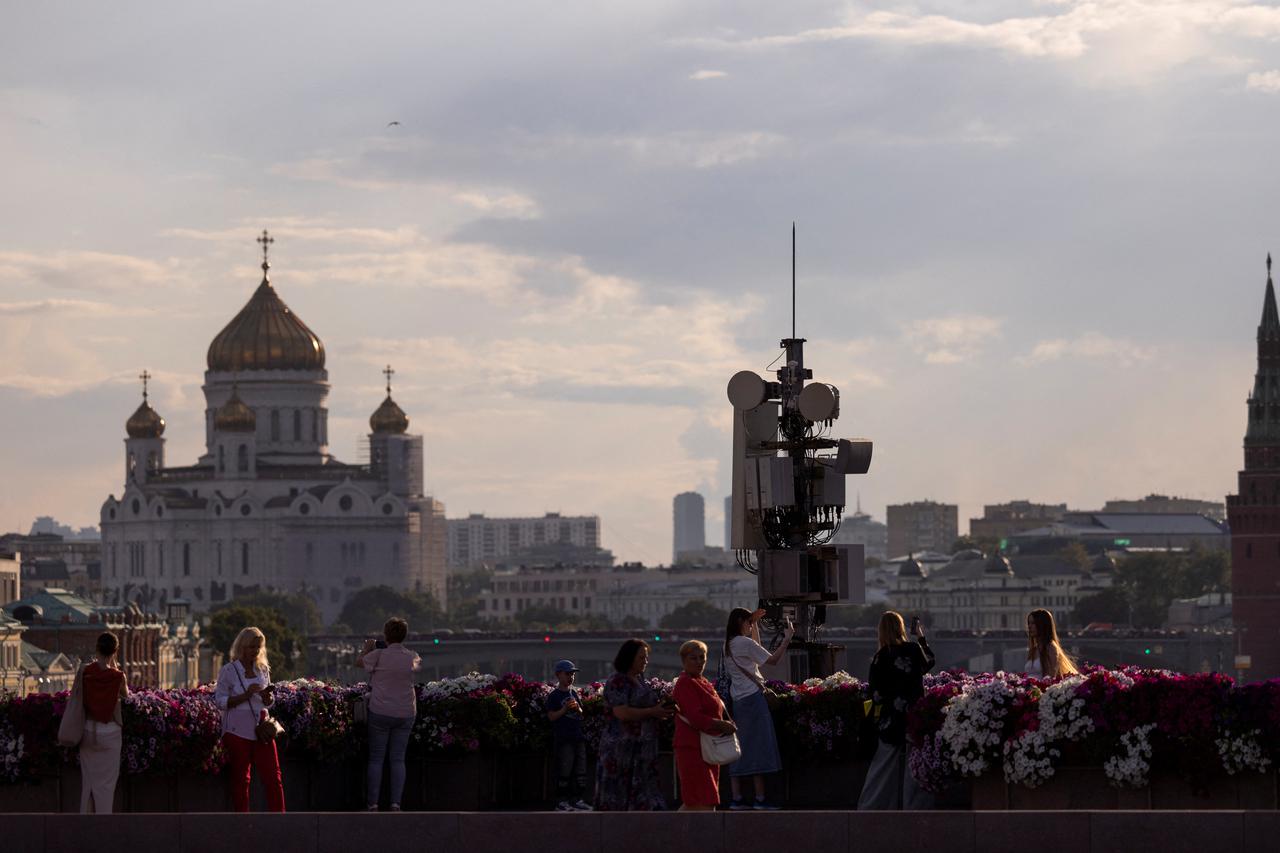 People gather on a bridge with the view on Christ the Savior Cathedral, in Moscow