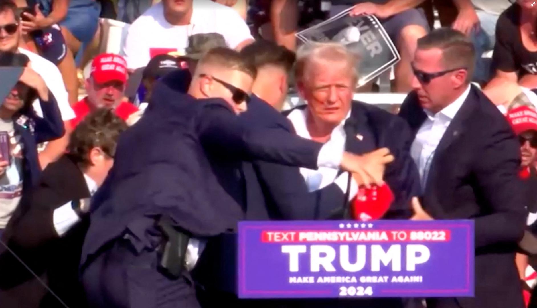 Republican presidential candidate and former U.S. President Donald Trump is assisted by security personnel after gunfire rang out during a campaign rally at the Butler Farm Show in Butler, Pennsylvania, U.S., July 13, 2024, in this screen grab taken from a video. REUTERS/Reuters TV Photo: REUTERS TV/REUTERS