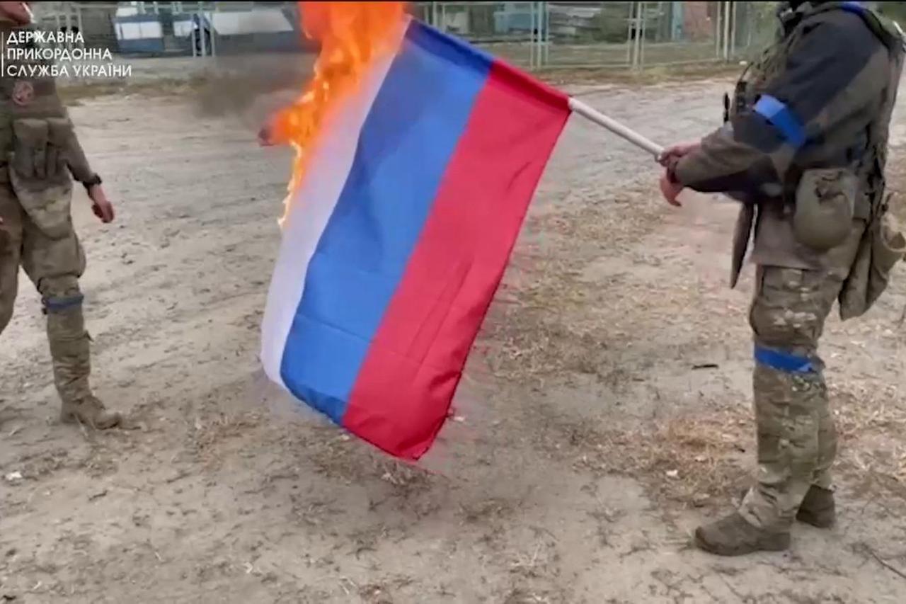 Ukrainian soldiers burn a Russian flag, in Vovchansk