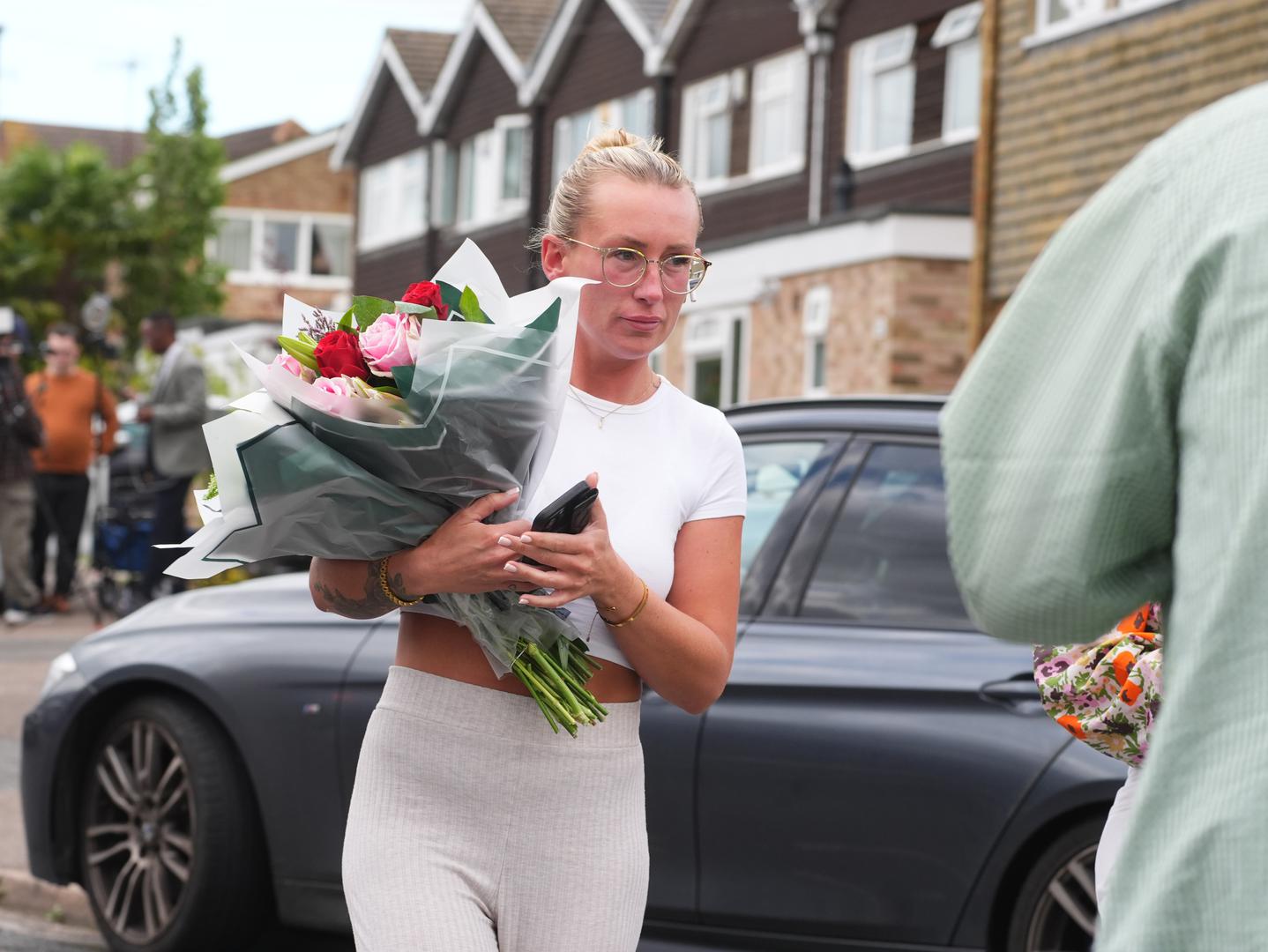 A woman delivers floral tributes near to the scene in Ashlyn Close, Bushey, Hertfordshire, where the wife and two daughters of a BBC sports commentator have been killed in a crossbow attack at their home. Carol Hunt, 61, who was married to BBC Five Live racing commentator John Hunt, and two of their daughters died in Ashlyn Close, Bushey, Hertfordshire, on Tuesday evening. A manhunt has been launched for Kyle Clifford, 26, from Enfield, north London, who is wanted by detectives investigating the murders of the three women. Picture date: Wednesday July 10, 2024. Photo: James Manning/PRESS ASSOCIATION