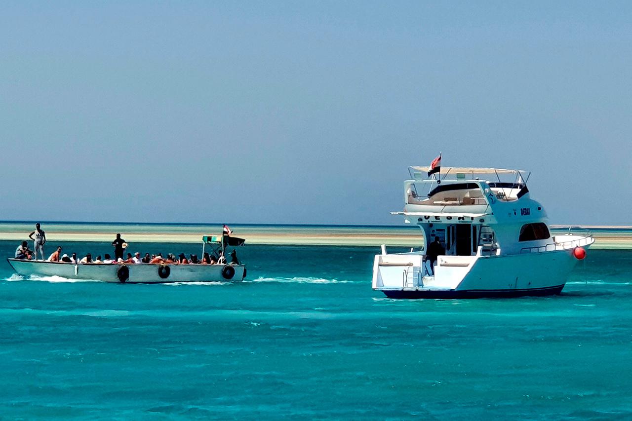 Tourists take a tour next to a docked yacht in the marina at the Egyptian Red Sea resort of Hurghada after a tourist boat sinks off Red Sea coast