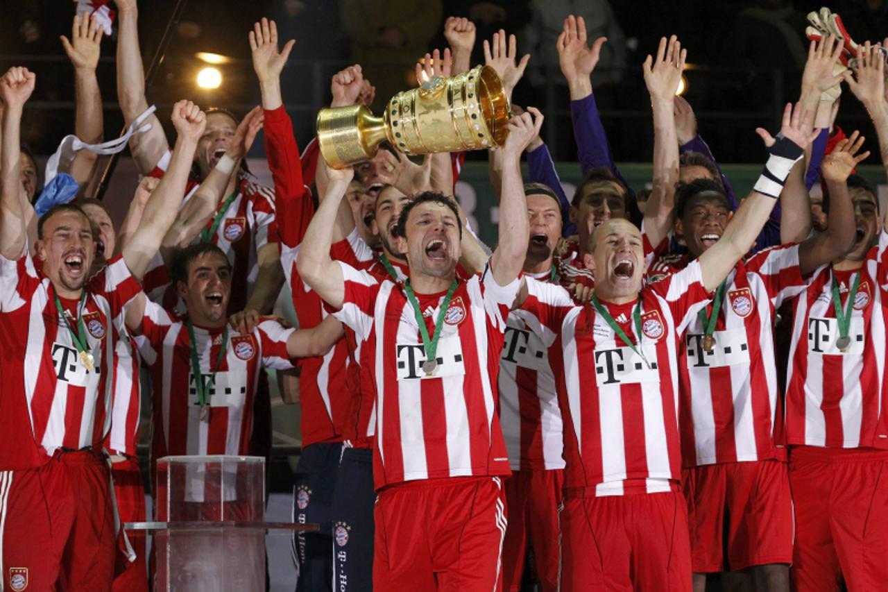 'Bayern Munich\'s team captain Mark Van Bommel holds the German Cup (DFB-Pokal) trophy after their 4-0 victory in the final match against Werder Bremen in Berlin, May 15, 2010. REUTERS/Kai Pfaffenbach