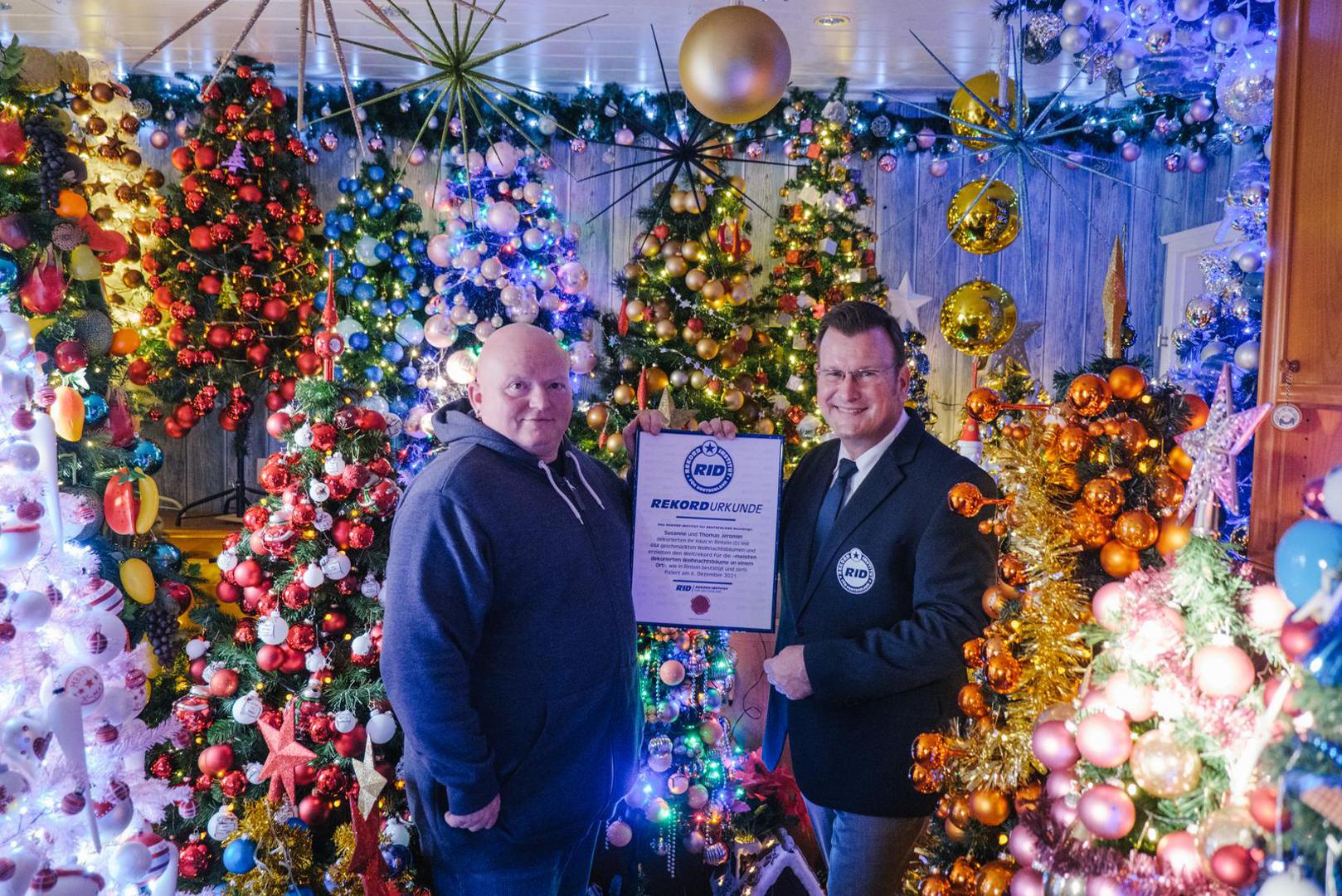 06 December 2021, Lower Saxony, Rinteln: Olaf Kuchenbecker (r), RID record judge, presents the record certificate to Thomas Jeromin. Thomas Jeromin has set a new world record with 444 Christmas trees in his house. The Record Institute for Germany was there on Monday to check and confirmed the record. Photo: Ole Spata/dpa