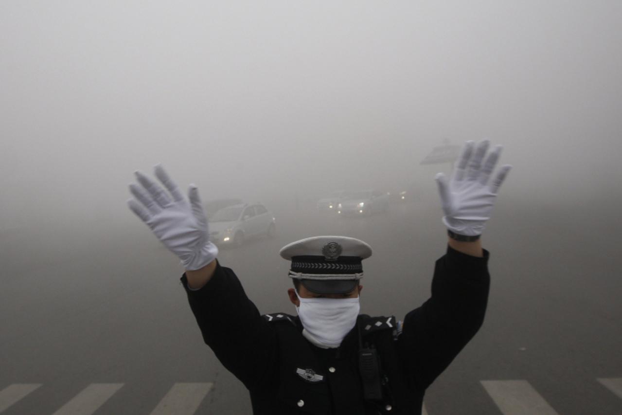 'A traffic policeman signals to drivers during a smoggy day in Harbin, Heilongjiang province, October 21, 2013. The second day of heavy smog with a PM 2.5 index has forced the closure of schools and h