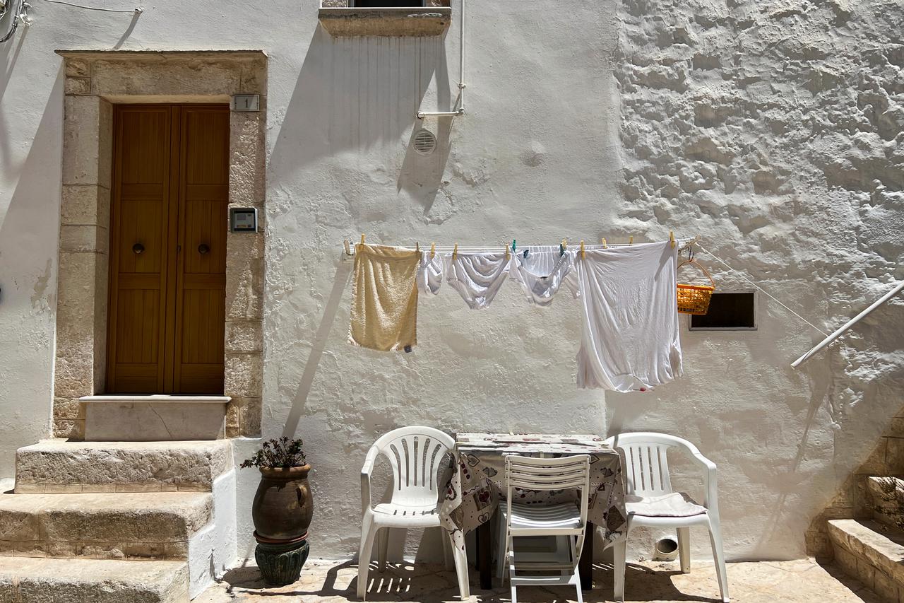 Clothes hang in the sun in front of the door of a house in Locorotondo